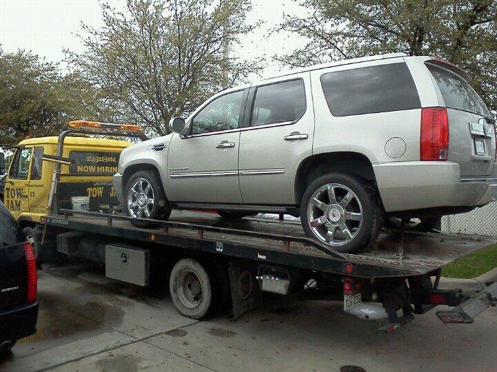 A silver SUV being transported on a Tow Jam flatbed tow truck by Tow Jam in Dallas, TX.