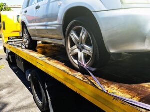 A silver SUV secured on a yellow flatbed tow truck for Spokane Towing Services in Spokane, WA.