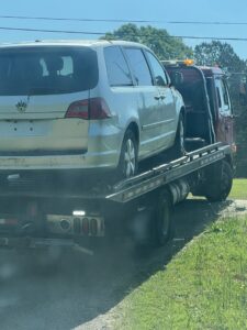 A silver Volkswagen minivan being transported on a flatbed tow truck by Grace to Grace Towing in Atlanta, GA.