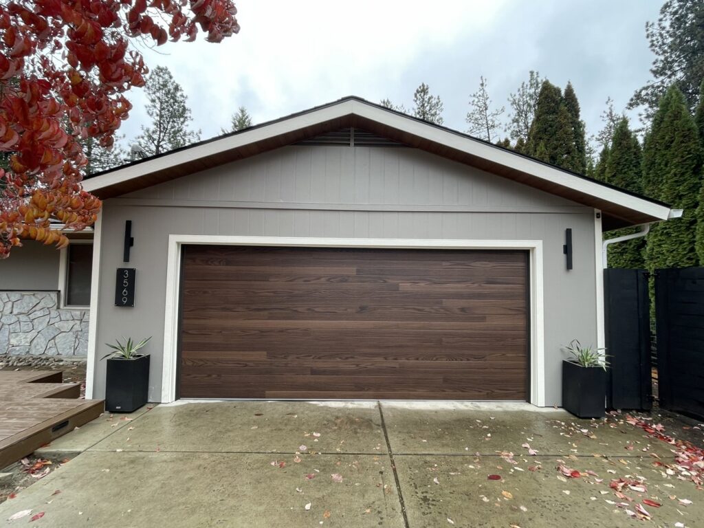 A single modern wood grain garage door installed on a residential home, a project by North Idaho Garage Door in Coeur d'Alene, ID.
