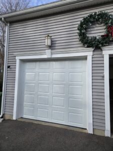 A newly installed single white garage door on a gray-sided house by Spring King Garage Doors in Middletown, CT