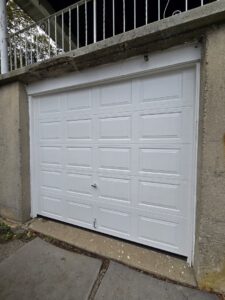 A newly installed single white panel garage door on a concrete structure by Spring King Garage Doors in Middletown, CT
