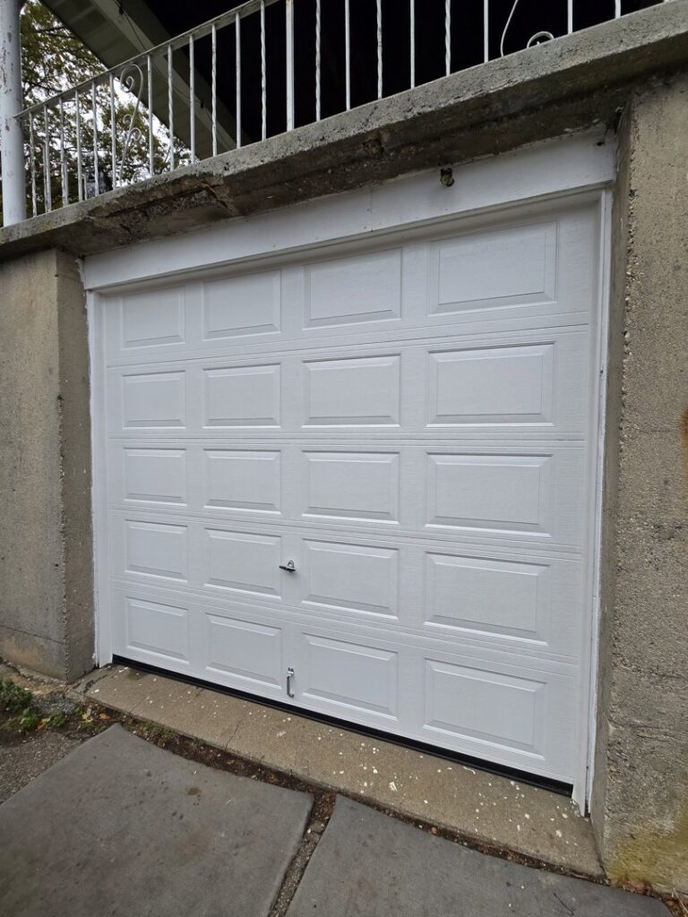 A newly installed single white panel garage door on a concrete structure by Spring King Garage Doors in Middletown, CT