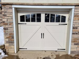 Single white X-brace style garage door with windows on a stone-faced home by Access Door Systems in Uniontown, PA.