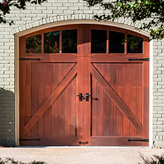 A single wooden garage door with an arched top and decorative hardware by Advance Garage Door, Inc. in Fargo, ND.