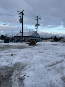 A skid steer loader clearing snow from a commercial parking lot, provided by Luna Landscape Pro in Racine, WI.