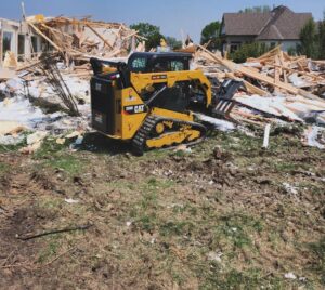 A skid steer loader moving debris from a demolished house at a job site for Allis Demolition & Hauling LLC in Omaha, NE