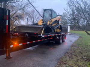 A yellow skid-steer loader from Just Take It, LLC. loaded onto a trailer for transport to a demolition site in Yorba Linda, CA.