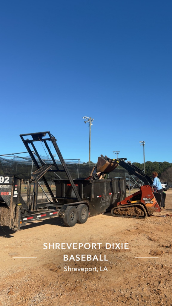 A skid steer loader actively loads debris into a roll-off dumpster for JP4 LLC, a demolition contractor in Bossier City, LA.