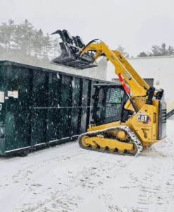 A skid steer loader loading demolition debris into a dumpster for Orion Demolition & Environmental Services, LLC in Albany, NY.
