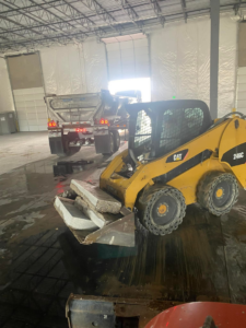 A skid steer loader from Independent Concrete Cutter Corp. removing concrete slabs inside a building in Denver, CO.