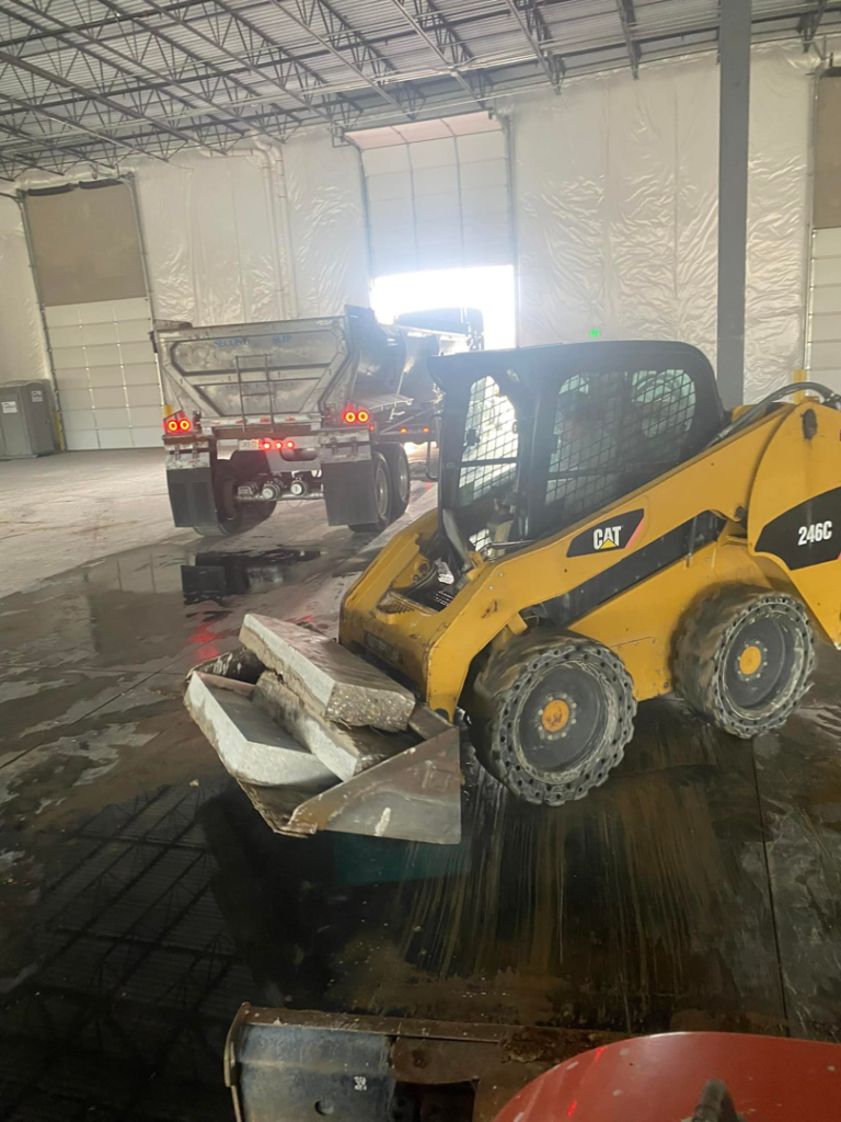 A skid steer loader from Independent Concrete Cutter Corp. removing concrete slabs inside a building in Denver, CO.