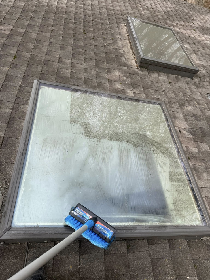 A dirty skylight on a roof being cleaned with a brush, showing the cleaning in progress by Exterior Wash Pro LLC in Springdale, AR.