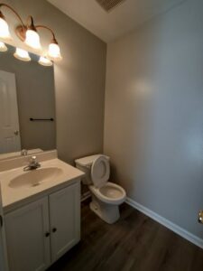 A small, clean bathroom with a white vanity and toilet, meticulously cleaned by Tessa's Cleaning Service in Chesapeake, VA.