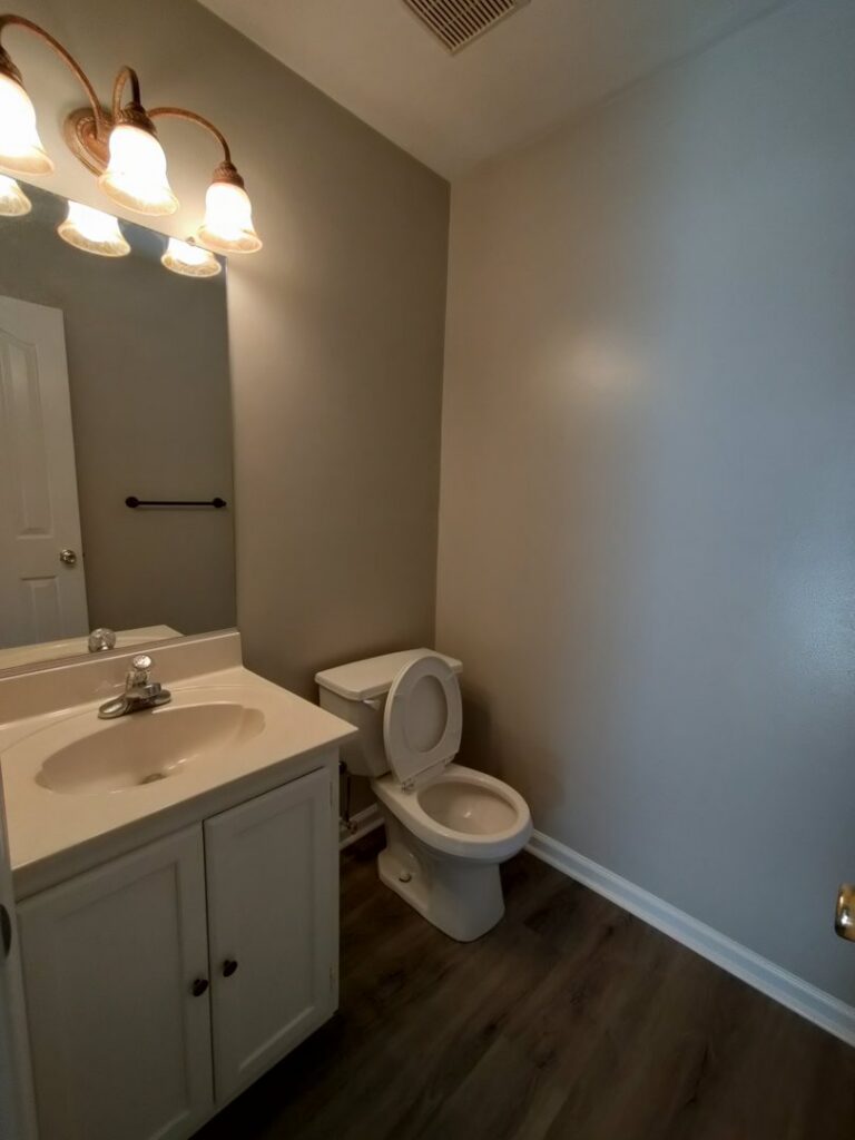 A small, clean bathroom with a white vanity and toilet, meticulously cleaned by Tessa's Cleaning Service in Chesapeake, VA.