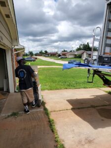 A SNEEDWORKS mover using a hand truck to move an item from a residential garage in Oklahoma City, OK.