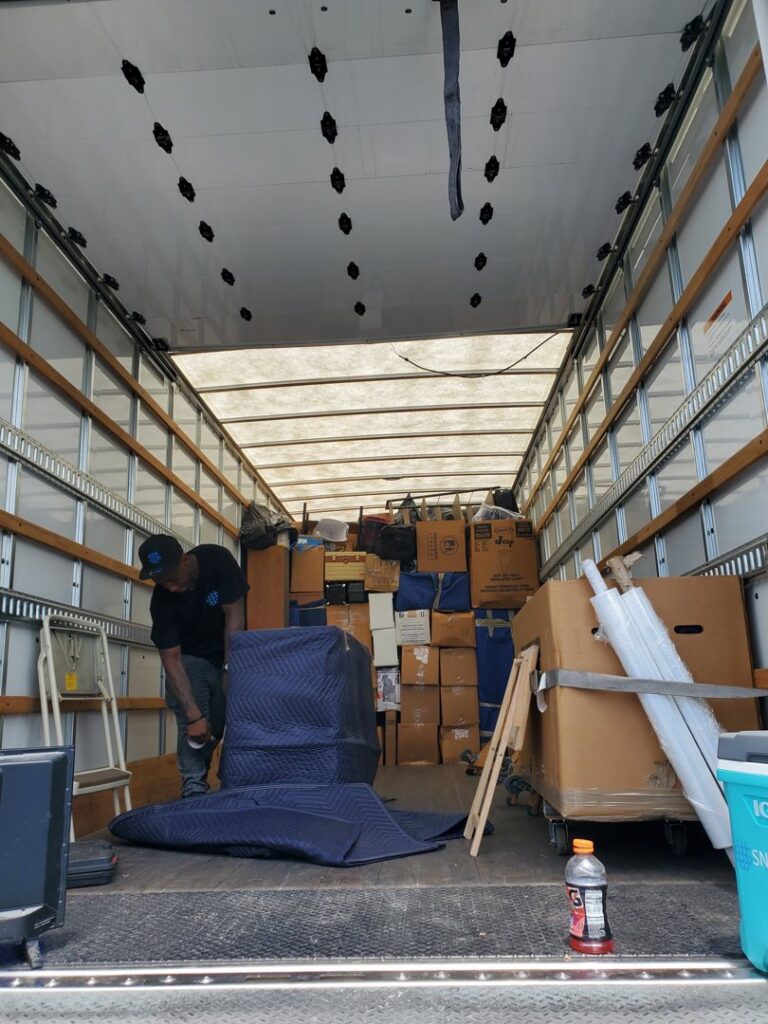 A SNEEDWORKS mover carefully packing and wrapping furniture inside a moving truck in Oklahoma City, OK.