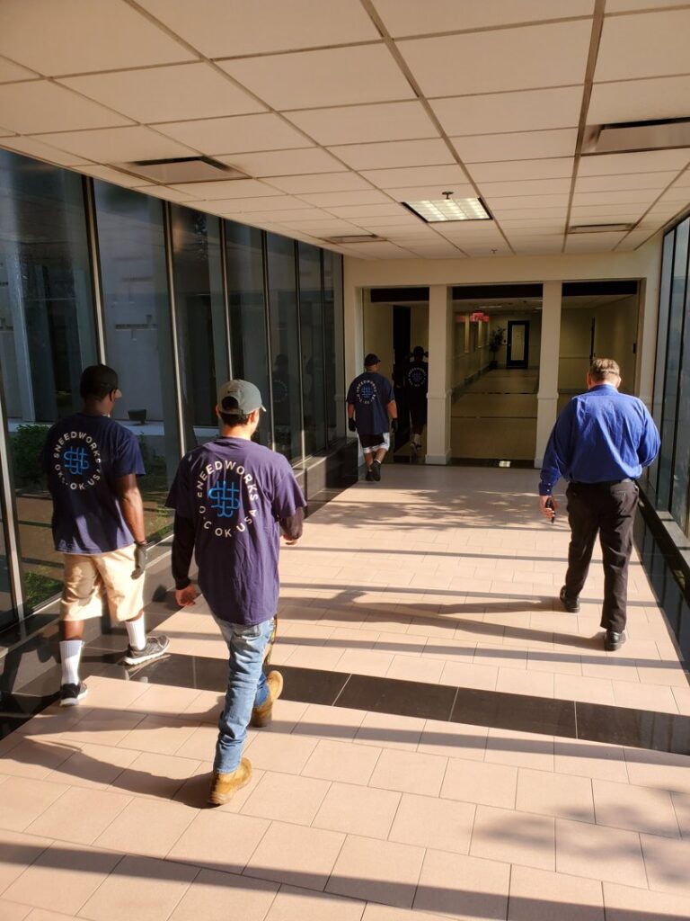 SNEEDWORKS movers in uniform walking down a commercial building hallway in Oklahoma City, OK, during a job.