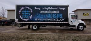 A SNEEDWORKS moving truck parked outside a commercial building in Oklahoma City, OK, ready for a moving service.