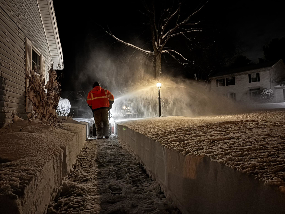 A professional using a snow blower to clear a path at night for 10.7 Property Solutions LLC in South Bend, IN