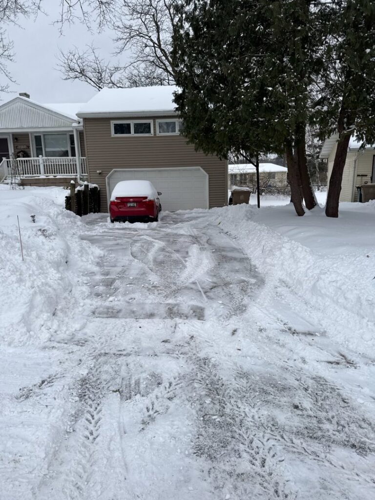 A residential driveway with snow cleared to the sides by Snow Scholars - Snow Removal By College Students in Madison, WI.
