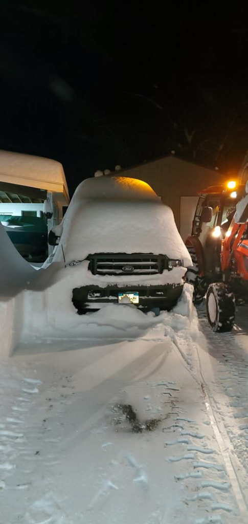 A snow-covered truck and a tractor with a plow ready for snow removal at TPM Snow Removal in Schenectady, NY.
