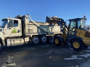 A dump truck being loaded with snow by a front-end loader for Rochester Ground Lawn & Snow Services in Rochester, MN.