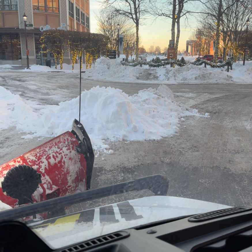 A snow plow clearing a commercial parking lot by AM Snow Removal & Lawn Care Services in Ankeny, IA.