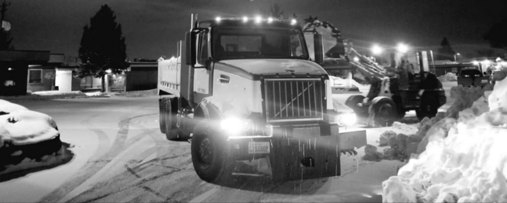 A snow plow truck with its lights on, ready for or after a snow removal job at night by Yakima Landscape Management in Yakima, WA.