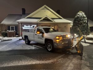 A snow plow truck from Rustic Ridge Landscaping clearing snow at Bank of Tennessee in Johnson City, TN.
