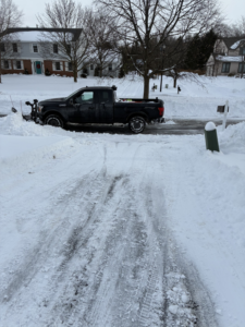 A snow plow truck from JRK Landscaping and Snow Removal clearing a residential driveway in Syracuse, NY.