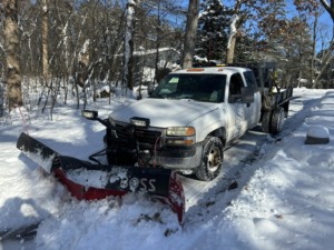A Simply Snow & Lawn LLC truck with a BOSS plow actively clearing snow from a driveway in Madison, WI.
