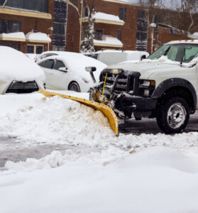 A snow plow truck clearing a parking lot, providing efficient snow removal by Green Castle Lawn Care and Pest Control in Ogden, UT.