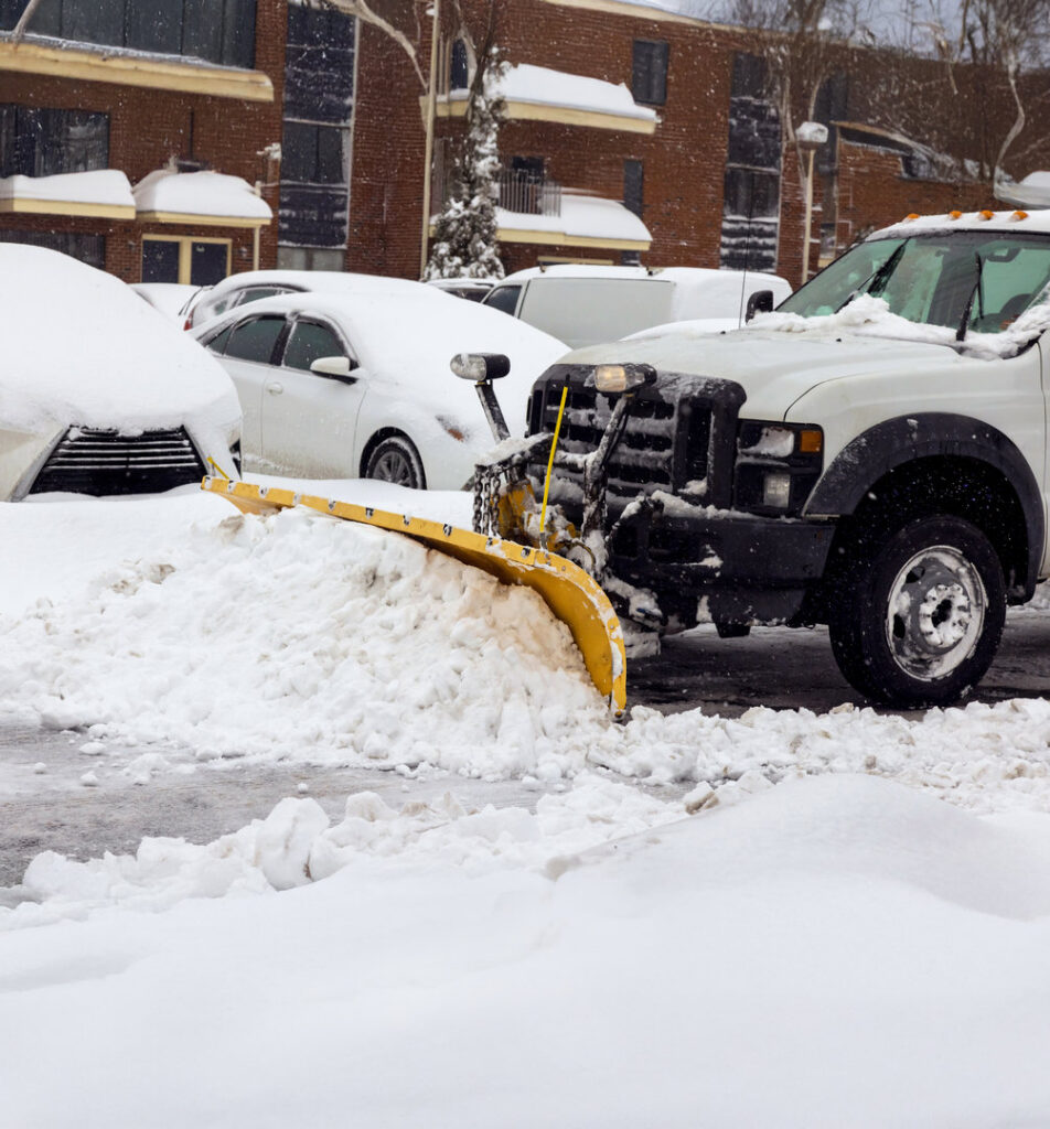 A snow plow truck clearing a parking lot, providing efficient snow removal by Green Castle Lawn Care and Pest Control in Ogden, UT.