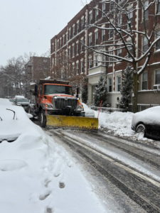 A snow plow truck clearing a residential street of snow for the City of Cambridge Department of Public Works in Cambridge, MA.