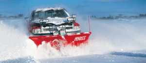 A red pickup truck with a snow plow actively clearing a snowy road for Dependable Snow Removal in Philadelphia, PA.