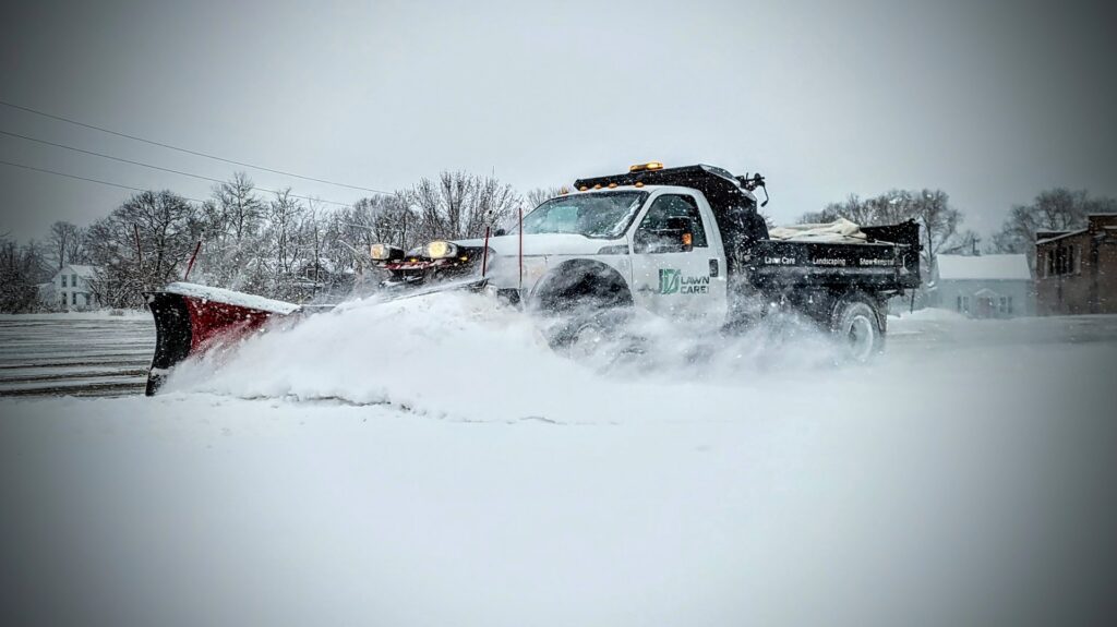 A JD Lawn Care LLC snow plow truck actively clearing a snowy road in Berea, OH.