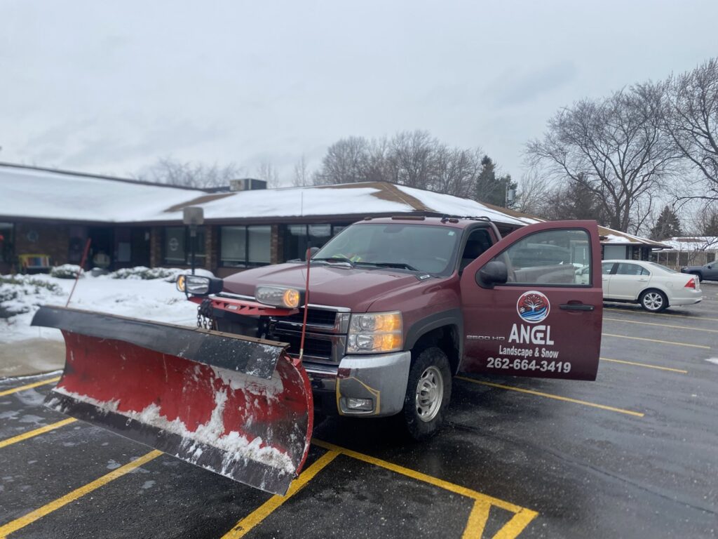 A red pickup truck with a snow plow ready for snow removal services by Angel Landscape & Snow Services Inc. in Racine, WI.