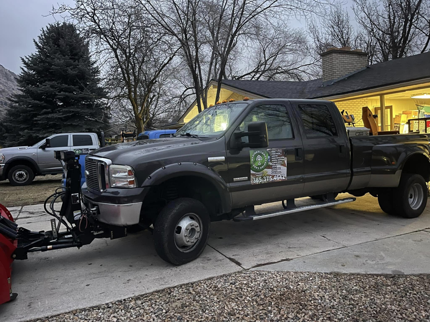 A dark pickup truck equipped with a snow plow and blower, ready for snow removal services by Medina's Landscape Care LLC in Layton, UT.