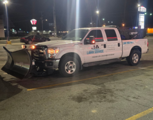 A JA Lawn Service, LLC pickup truck with a snow plow and salt spreader ready for snow removal at night in Fort Wayne, IN.