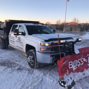 A Silver Peak Services snow plow truck with a red BOSS plow ready for snow removal in Colorado Springs, CO.
