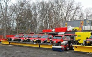 A line of red snow plow trucks and various snow removal equipment ready for service by The Groundskeeper Inc. in Fort Collins, CO.