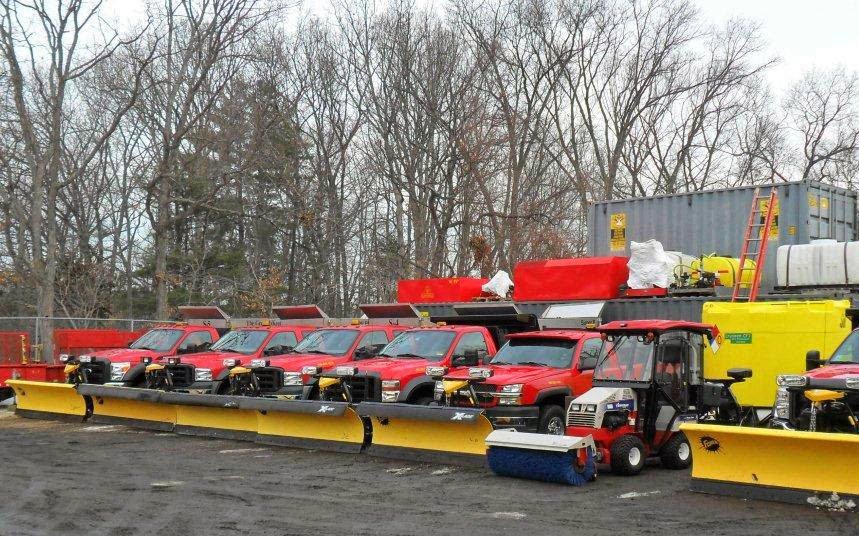 A line of red snow plow trucks and various snow removal equipment ready for service by The Groundskeeper Inc. in Fort Collins, CO.