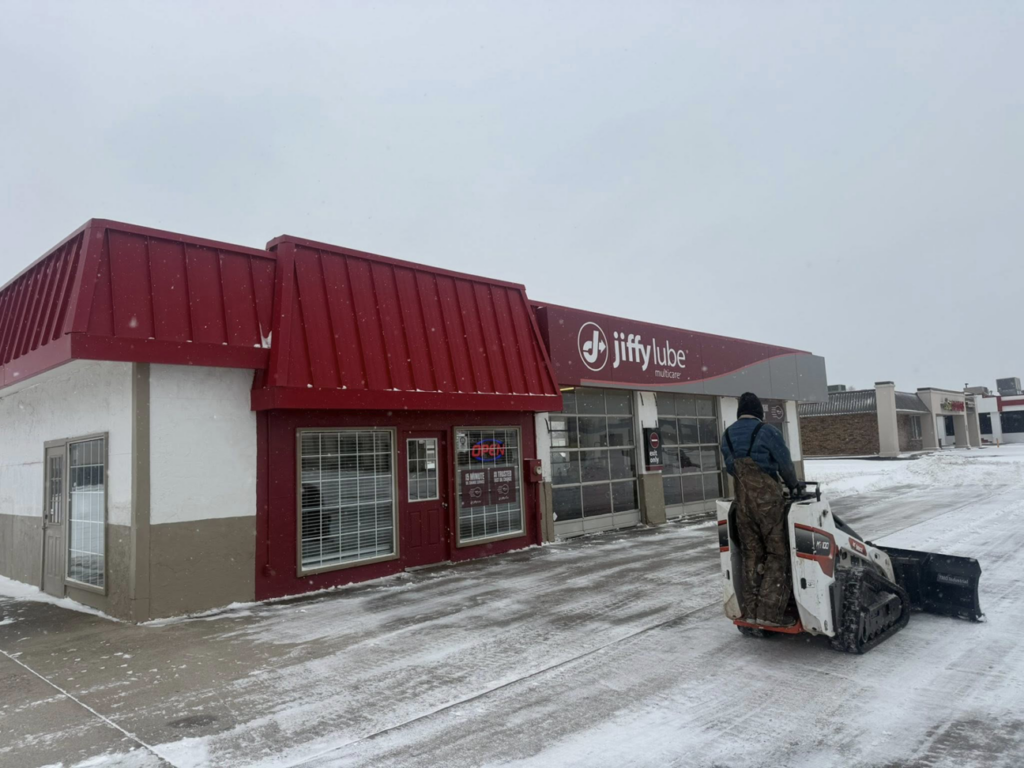 Snow plowing a Jiffy Lube parking lot with a skid-steer loader by Trusted Fencing LLC in Moore, OK.