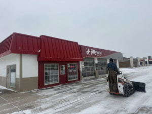 Snow plowing a Jiffy Lube parking lot with a skid-steer loader by Trusted Fencing LLC in Moore, OK.