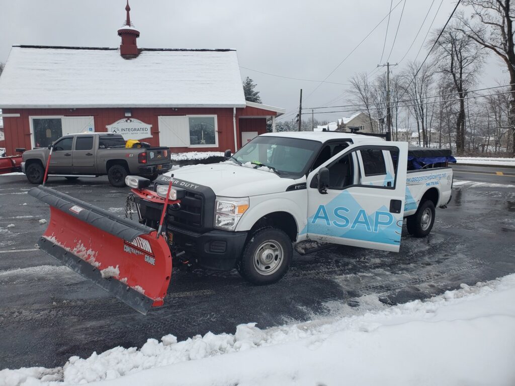 A snow plowing truck with snow on its plow, parked after completing a job for American Snow Plowing Services in Rockville, MD.