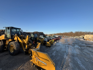 A fleet of snow removal equipment, including a front-end loader and skid steers with plows, ready for service at C&S Lawncare in Ann Arbor, MI.