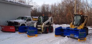 A fleet of snow removal equipment, including trucks and skid steers, parked in the snow for Rochester Ground Lawn & Snow Services in Rochester, MN.
