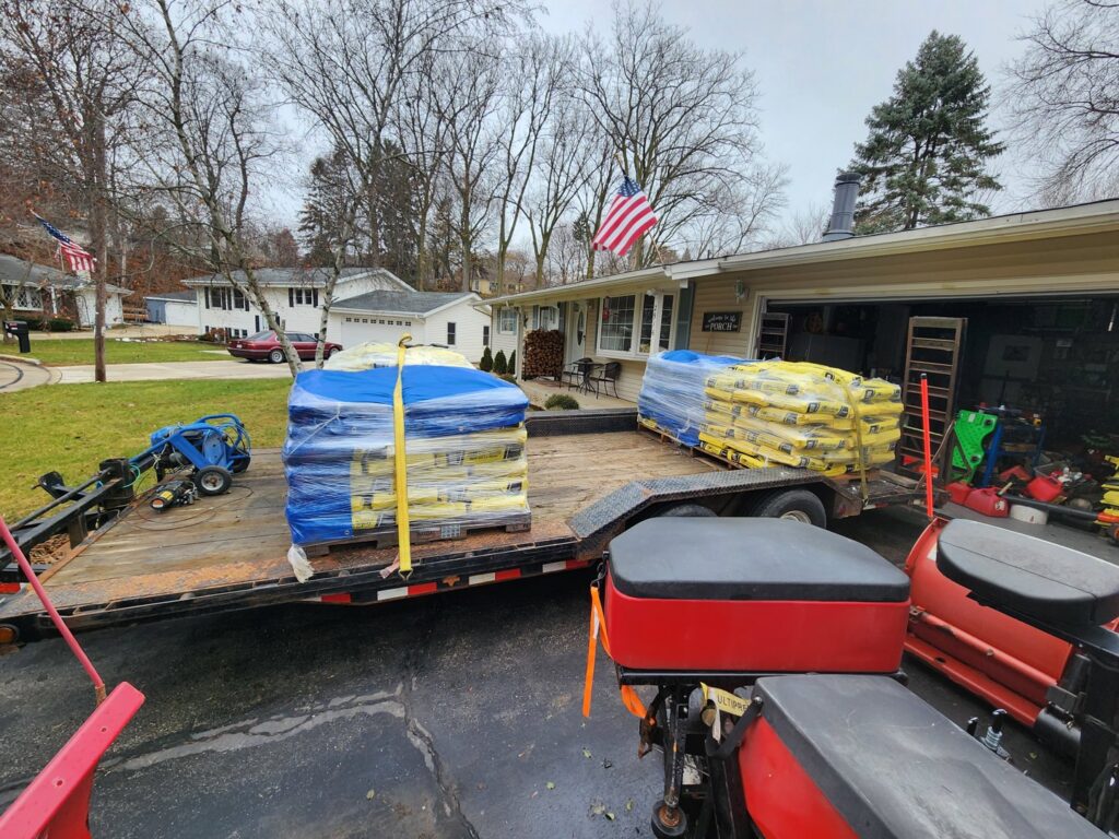 A trailer loaded with bags of salt and snow spreaders, essential equipment for snow removal by JCO Landscape & SNOW in Racine, WI.