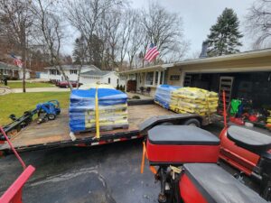 A trailer loaded with bags of salt and snow spreaders, essential equipment for snow removal by JCO Landscape & SNOW in Racine, WI.